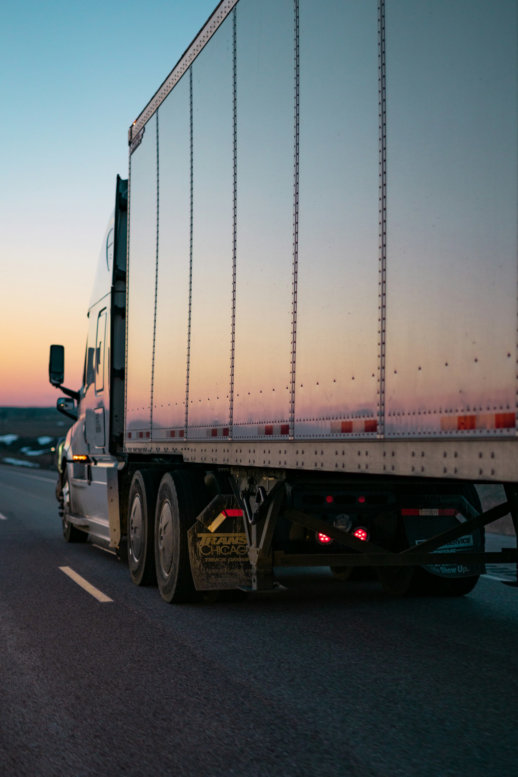 Dry van trailer rolling down the highway at dusk